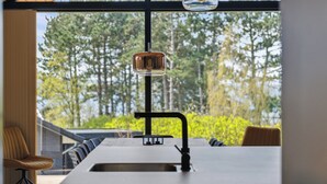 A modern kitchen with a large window, a sink, and a bar area. - Impressive holiday cottage, by the Helsnæs Bay! (Millinge)