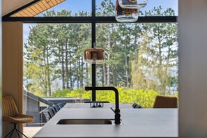 Eine moderne Küche mit großem Fenster, einer Spüle und einer Bar.