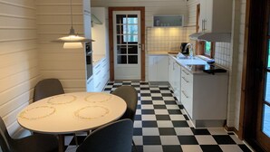 Une cuisine avec un carrelage à motifs, des placards blancs, un évier et un coin repas comprenant une table et des chaises.