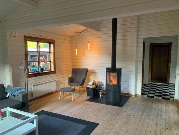 A cozy living room with a fireplace, a sofa, a chair, and a window with a view.