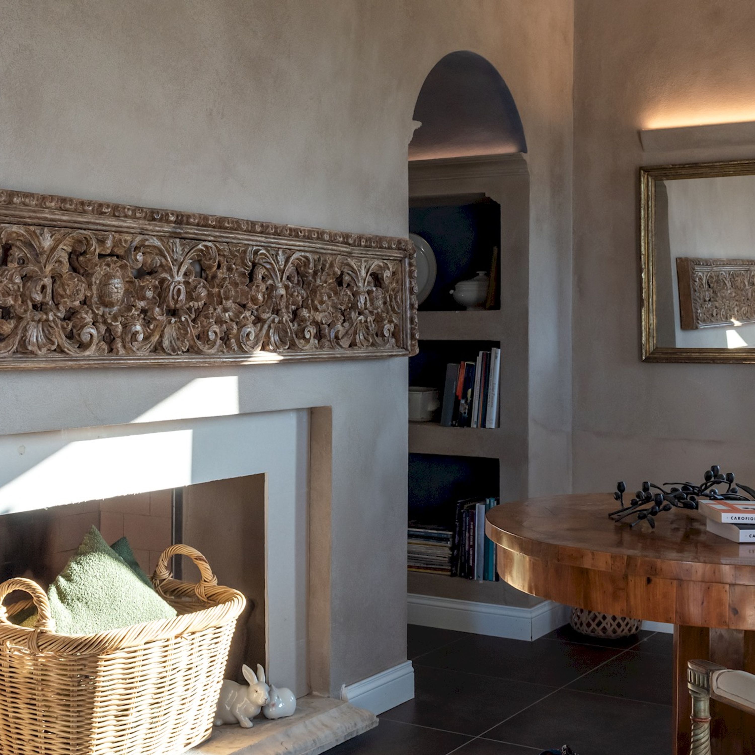 A living room with a fireplace, a bookshelf, a wooden table, and a wicker basket.