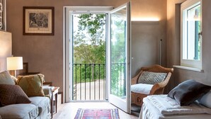 Una habitación acogedora con un amplio ventanal corredera que da a un balcón, una alfombra estampada y una silla de mimbre.