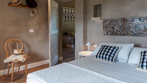 Un dormitorio con una cama, una silla y una puerta que da a otra habitación.