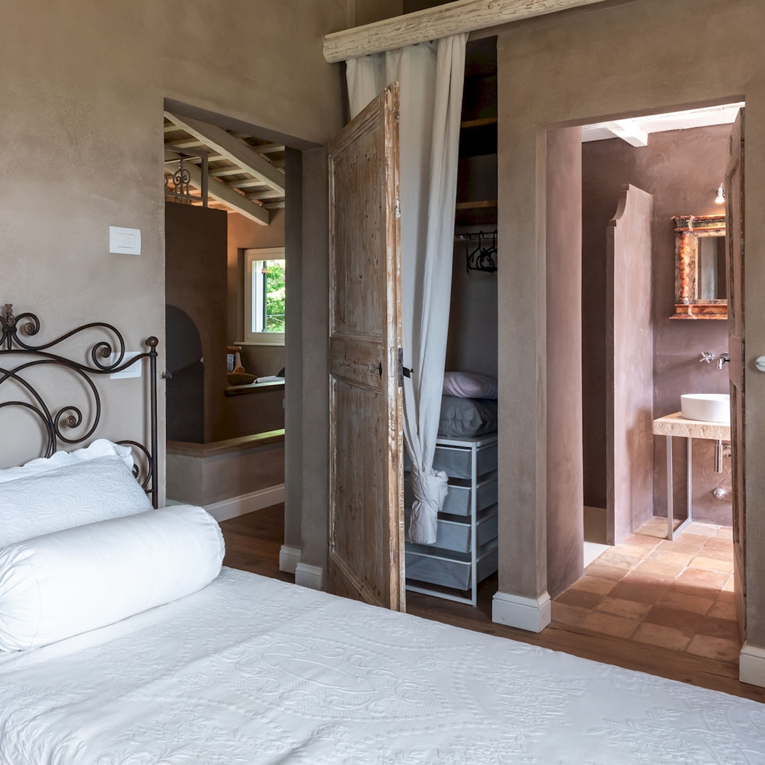 Un dormitorio con cama, armario y baño visible a través de una puerta abierta.