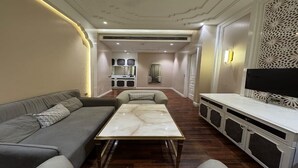 A modern living room with a sofa, a coffee table, and a TV. - Devrath By Big Bite Resort (Meerut)