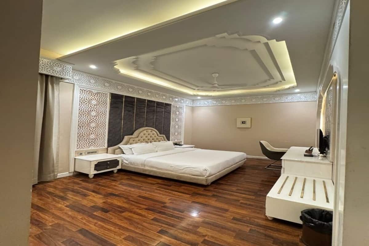 Quarto com uma cama grande, mesa de cabeceira, cômoda e uma cadeira.
