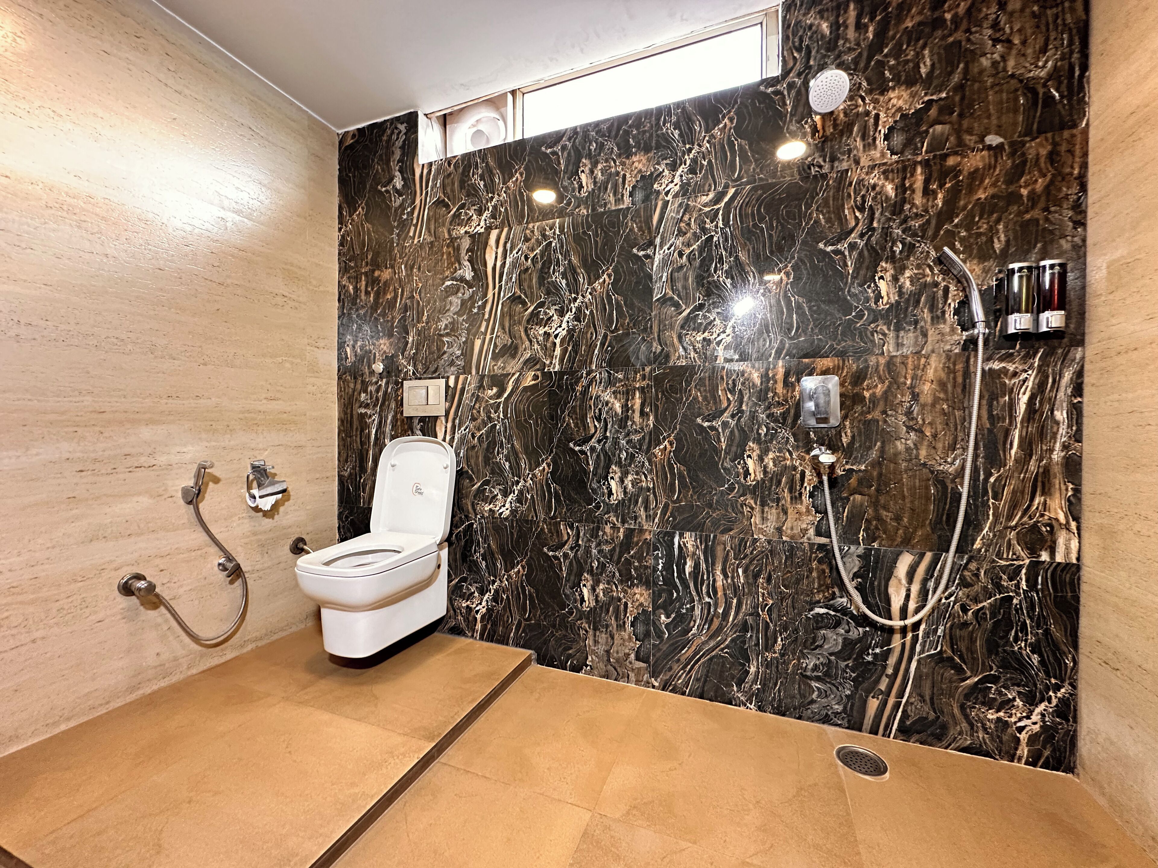 A modern bathroom with a marble wall, a toilet, a shower, and a sink.