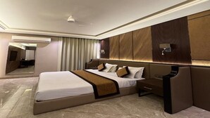 A modern hotel room with a large bed, a nightstand, a mirror, and a wall-mounted TV. - Devrath By Big Bite Resort (Meerut)