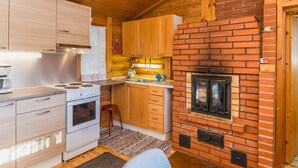 Eine kleine Küche mit Holzschränken, einem eingebauten Herd und einem Kamin aus Backsteinen.