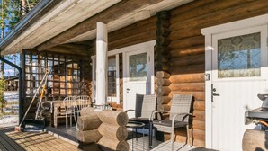Eine Blockhütte mit einer Holzterrasse, Sitzgelegenheiten im Freien und Grillplatz.