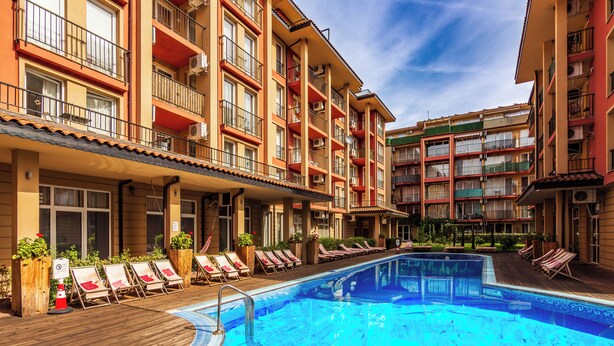 Un hôtel doté d’une piscine, de plusieurs balcons et de chaises longues.