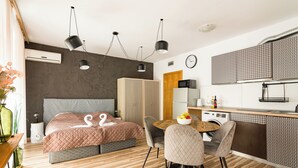 Une chambre moderne avec un grand lit, une table à manger et un coin cuisine.