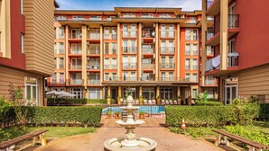Un hôtel à plusieurs étages doté d’une cour intérieure où se trouvent une fontaine, des bancs et une piscine.