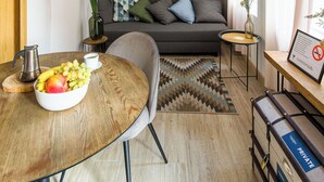 Un salon moderne avec une table ronde en bois, un canapé gris et une œuvre d’art murale.