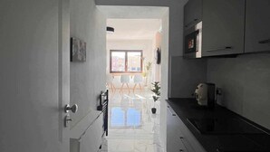 Une cuisine moderne avec un sol en marbre blanc, un plan de travail noir et des armoires grises.