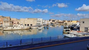 Un port de plaisance avec des bateaux amarrés, un ciel dégagé et des bâtiments en arrière-plan.