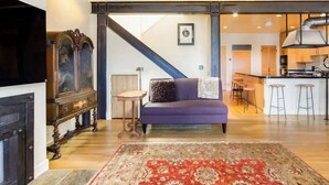 A living room with a sofa, a patterned rug, a fireplace, and a kitchen area visible through an open doorway. - Two  Bedroom, Two Newly Renovated Bathrooms, Deck (San Francisco)