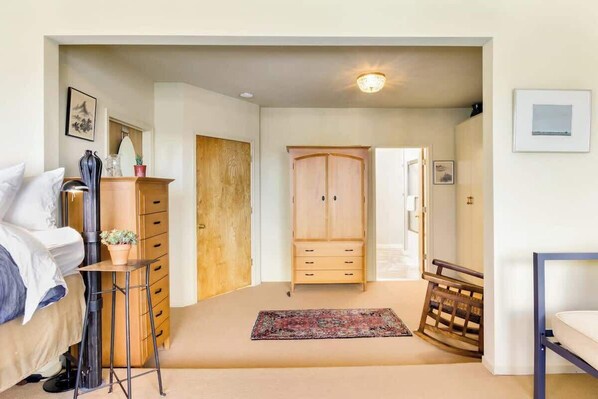 Une chambre à coucher comprenant un lit, une commode, une armoire et une petite table sur laquelle est posée une plante.