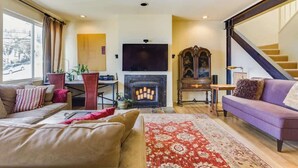 A living room with a fireplace, a sofa, a television, and a staircase. - Two  Bedroom, Two Newly Renovated Bathrooms, Deck (San Francisco)