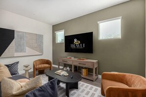 Een moderne woonkamer met een flatscreen televisie, een bank, een salontafel en een console met boeken.