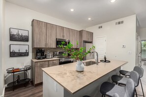 Una cocina moderna con armarios de madera, microondas integrado, cafetera y fregadero.