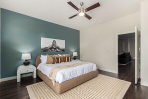A bedroom with a bed, a ceiling fan, a nightstand, a lamp, a wall-mounted picture, and a door leading to another room. - Macallister 1007|N Scottsdale|Close2Golf|Htd Pool (Scottsdale)
