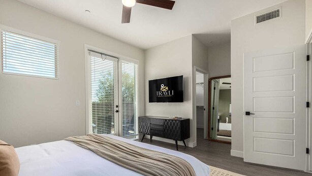 A bedroom with a bed, a TV, a dresser, and a door leading to another room. - Macallister Luxe 1008 | Close to Golf |Heated Pool (Scottsdale)