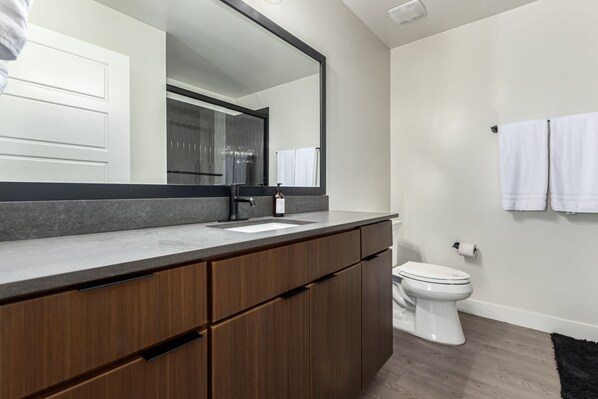 A modern bathroom with a large mirror, a sink, a toilet, and wooden cabinets. - Macallister Luxe 1008 | Close to Golf |Heated Pool (Scottsdale)