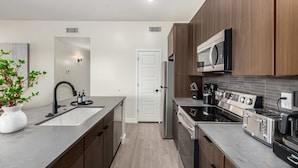 A modern kitchen with wooden cabinets, stainless steel appliances, and a large island with a sink and faucet. - Macallister Luxe 1008 | Close to Golf |Heated Pool (Scottsdale)