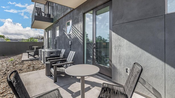 A modern outdoor patio with a table and chairs, a grill, and a balcony. - Macallister Luxe 1008 | Close to Golf |Heated Pool (Scottsdale)