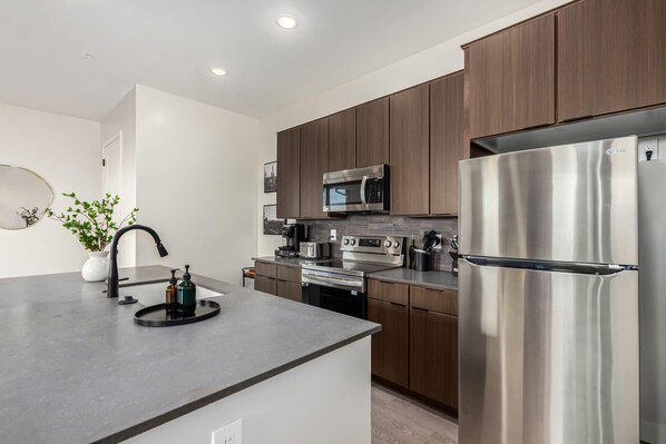 A modern kitchen with stainless steel appliances, wooden cabinets, and a central island. - Macallister 2006|Close to Golf|Htd Pool|BBQ (Scottsdale)