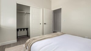 Ein Schlafzimmer mit einem Bett, einem Kleiderschrank und einer Tür zu einem anderen Raum.