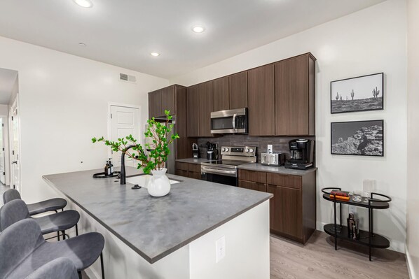 A modern kitchen with a central island, stainless steel appliances, and a coffee machine. - Macallister 2008|Heated Pool|Close 2 Golf|BBQ|View (Scottsdale)