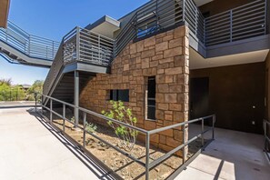 A modern building with a stone facade, metal railings, and a staircase leading to an upper level.
