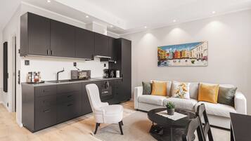 A modern kitchen with dark cabinets, a white chair, and a dining area with a table and chairs.