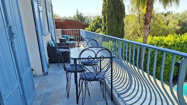 A patio with a table and chairs, a wicker bench, and a railing.