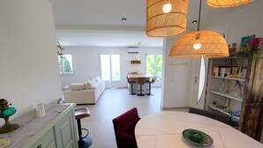 A modern kitchen with a dining area, a white sofa, and a red chair.