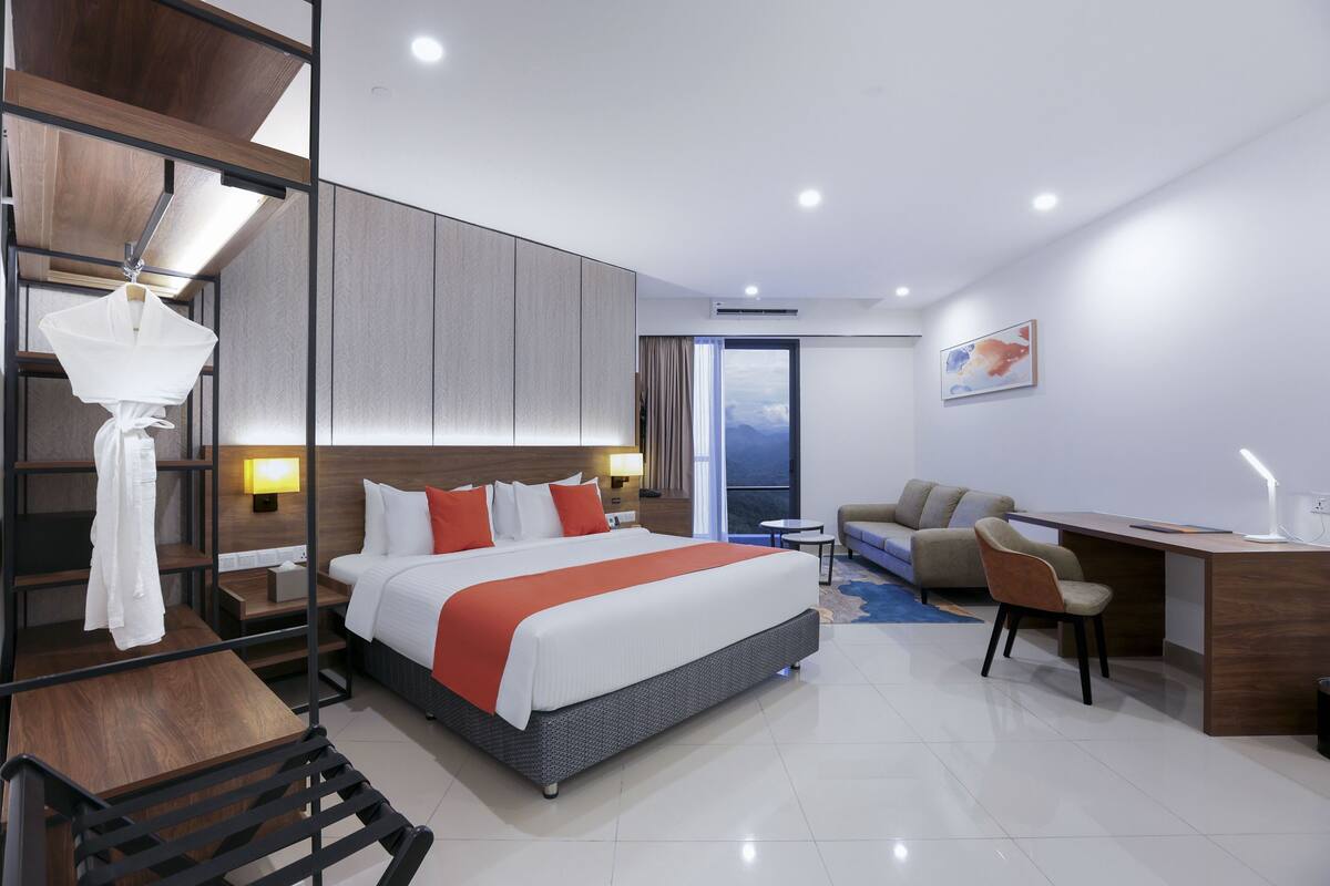 Una habitación de hotel moderna con una cama grande, un escritorio, un sofá y vistas al exterior.