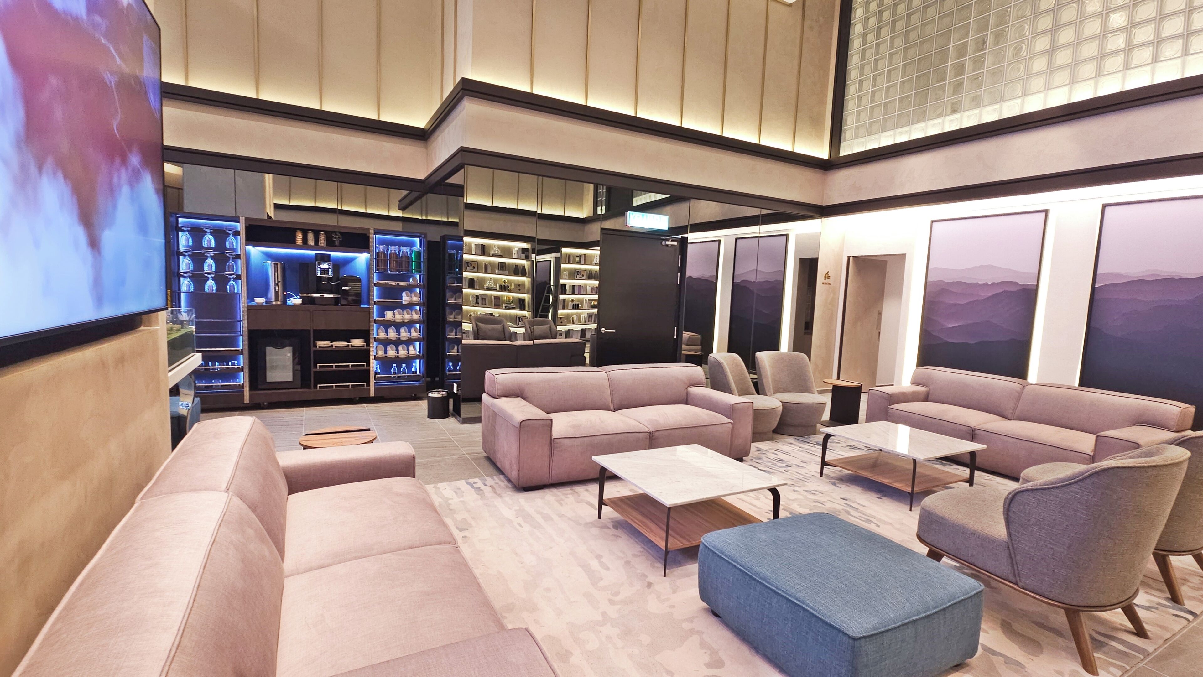 A modern lounge area with sofas, armchairs, and a coffee table. There are shelves with books and decorative items.