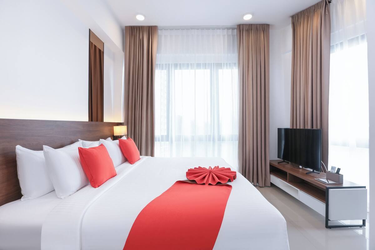 Una habitación de hotel moderna con una cama grande, un televisor y un escritorio con una silla.