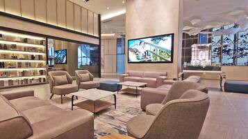 A modern lobby with sofas, armchairs, a coffee table, and a bookshelf.
