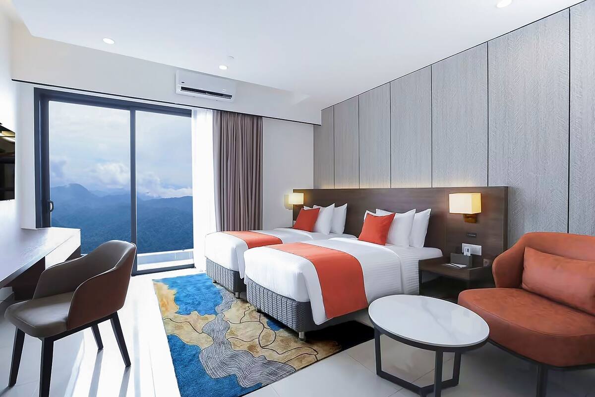 Habitación de hotel con una cama grande, un escritorio, una silla, una mesita y vistas a las montañas.