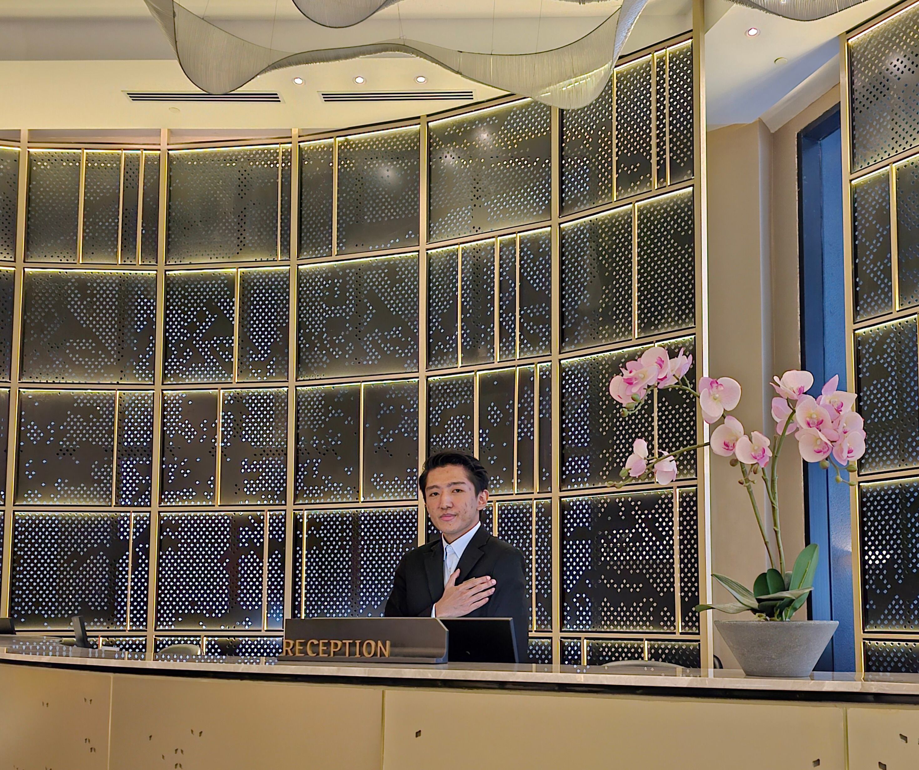 En reception med et moderne design, med et gitter af glaspaneler og en orkidé.