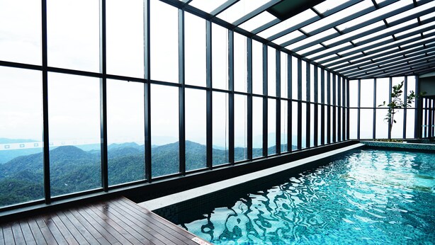 A swimming pool with a view of a forested mountain range through large windows. - Wyndham Ion Majestic Genting Highlands (Genting Highlands)