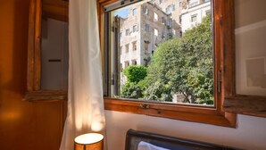 Una habitación con ventana que da a un edificio y zonas verdes.