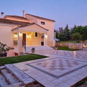 A two-story house with a tiled patio and a stone wall. - Utopia Beach Villa in Ionian Islands (Corfu)