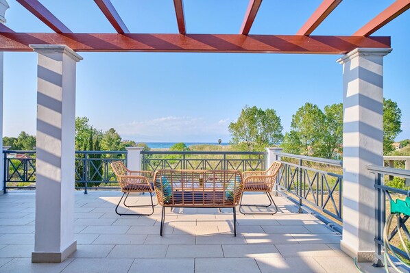 A covered outdoor seating area with a view of the sea.