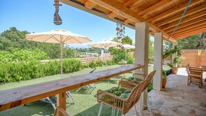 An outdoor patio with a wooden table and wicker chairs, surrounded by umbrellas and potted plants. - Villa Villekulla in Ionian Islands (Corfu)