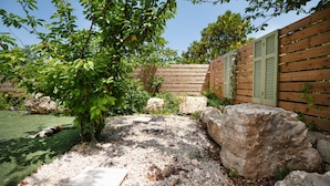 A garden with a wooden fence, a tree, and a rock. - Villa Villekulla in Ionian Islands (Corfu)