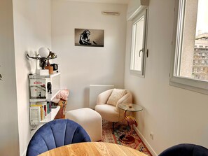 Relax in a serene space with a cozy seating area, bookshelf, and city view.